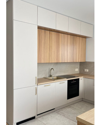 A modern, custom-built kitchen with beige cabinet fronts, wood accents, and gold handles is the perfect fit for elegant interior