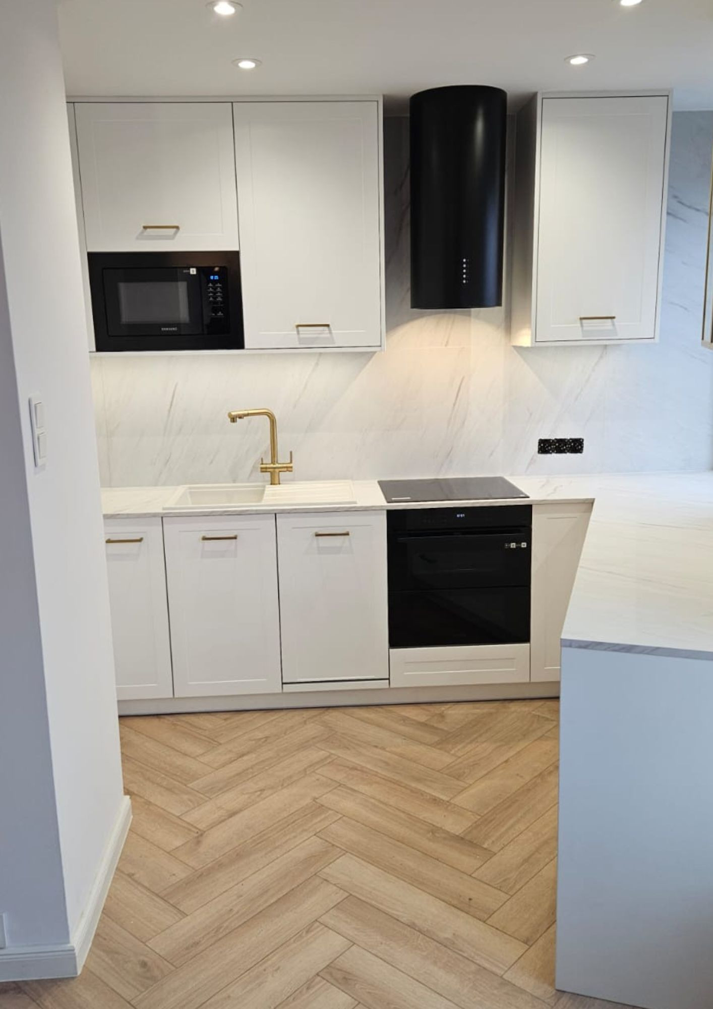 A small, custom-built white kitchen in an apartment building. A small, custom-built white kitchen in an apartment building.