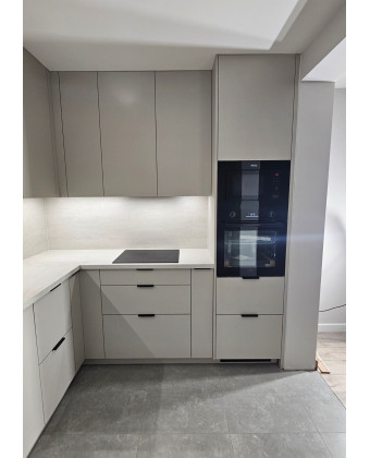 Modern cashmere-colored kitchen with black accents in Leszno