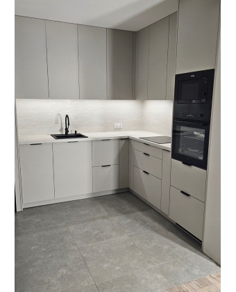 Modern cashmere-colored kitchen with black accents in Leszno