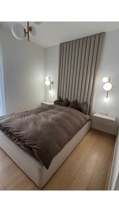 A bed with vertical upholstered panels on the wall