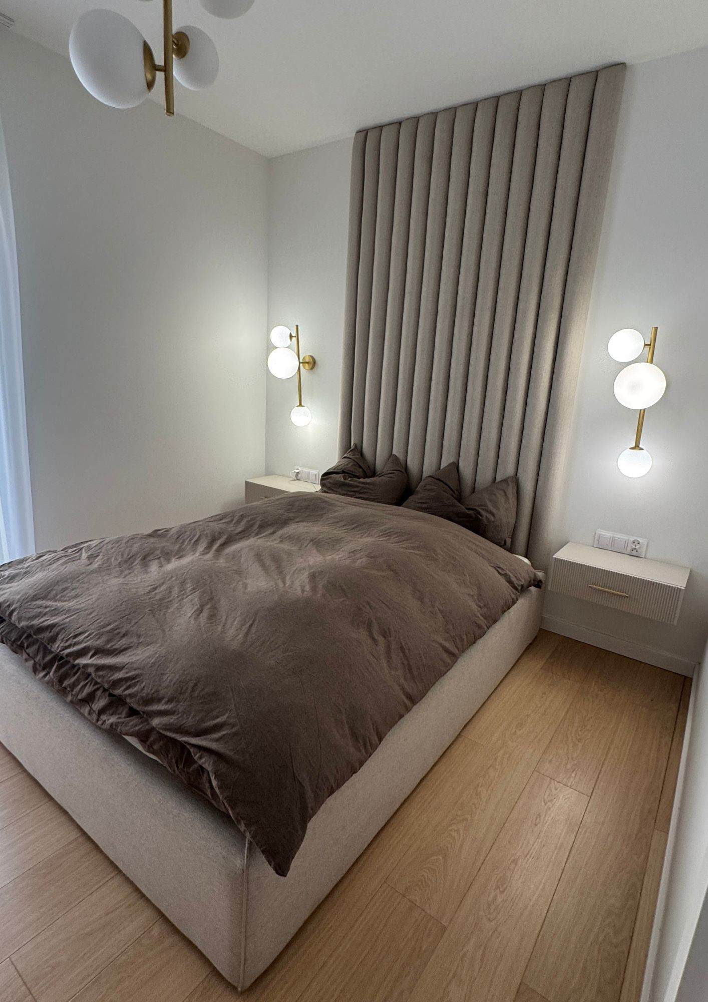 A bed with vertical upholstered panels on the wall