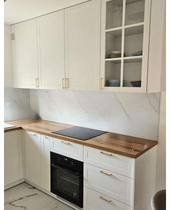 A white kitchen with a wooden countertop and gold handles in a classic style