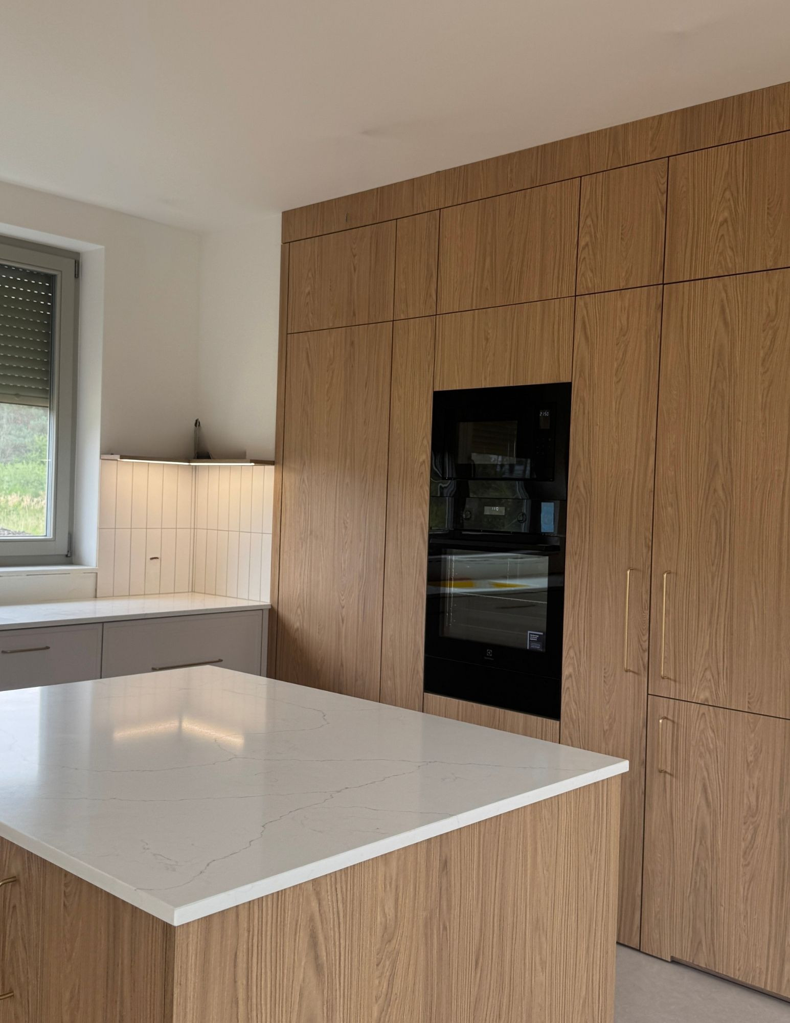 Elegancka kuchnia z kaszmirowymi frontami i wysoką zabudową do sufitu Elegancka kuchnia z kaszmirowymi frontami i wysoką zabudową do sufitu