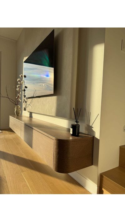 The LAVENA wall-mounted TV cabinet, made of stained oak veneer, in a modern living room
